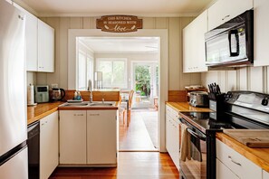 Une cuisine avec des armoires blanches, un four à micro-ondes, une cuisinière et une pancarte sur laquelle on peut lire : « Cette cuisine est préparée avec amour. »