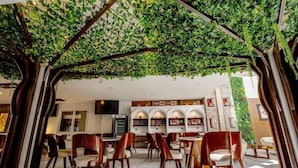 Un restaurante con jardín en el techo, sillas de madera y una pared con estanterías que exhiben objetos.