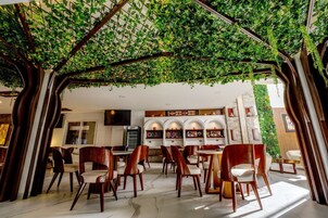 Un restaurante con jardín en el techo, sillas de madera y una pared con estanterías que exhiben objetos.