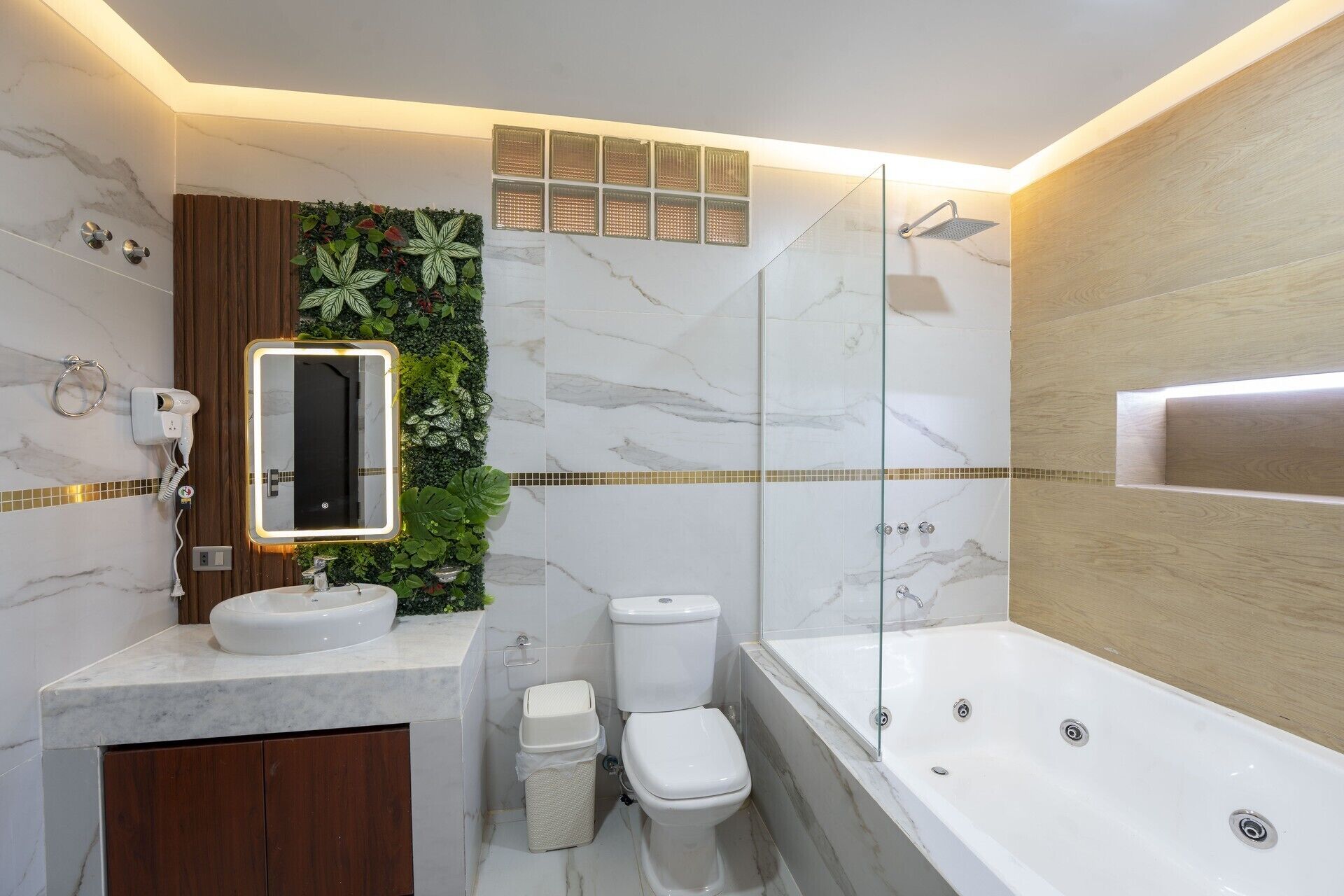 Une salle de bain moderne avec un meuble-lavabo en marbre, une cabine de douche en verre et un mur végétal intégré.
