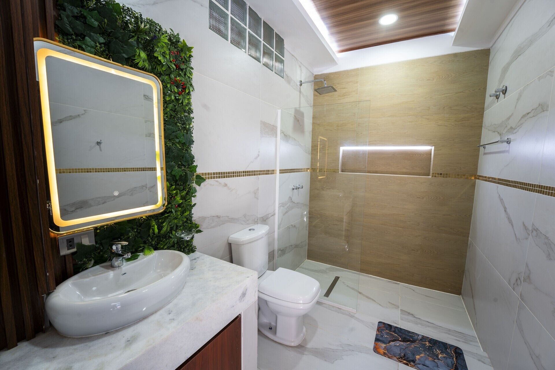 A bathroom with a large mirror, a sink, a toilet, and a shower area.
