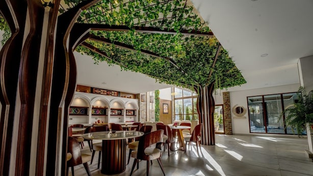Un comedor amplio con techo alto, vigas de madera arqueadas y vistas al exterior.