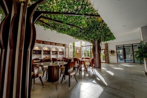 Un comedor amplio con techo alto, vigas de madera arqueadas y vistas al exterior.
