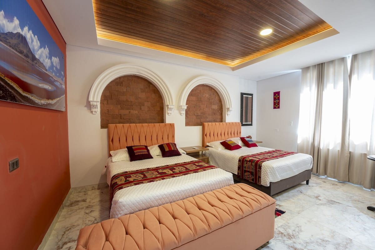 Un dormitorio con dos camas, piso de mármol, techo de madera y un cuadro en la pared.
