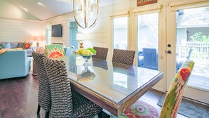 A dining area with a glass table, woven chairs, and a 'Welcome' sign. - Slow Down & Reconnect in Renovated, Dog-Friendly Cottage, Four Minutes to Beach w/ Great Back Dec (Kiawah Island)