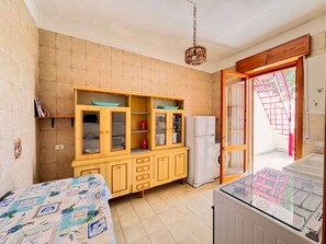 Eine kompakte Küche mit integriertem Schrank, einem Kühlschrank und einem Esstisch mit gemustertem Tischläufer.