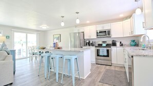 Uma cozinha moderna com armários brancos, eletrodomésticos de aço inoxidável e uma ilha central com banquetas.