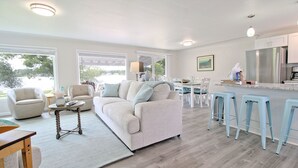 Uma sala de estar ampla com sofá, poltronas e mesa de jantar.