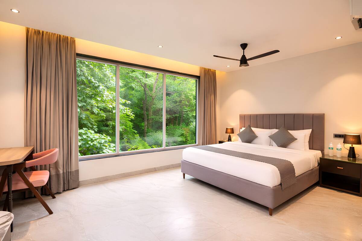 A modern bedroom with a large window, a bed, a desk, and a chair.