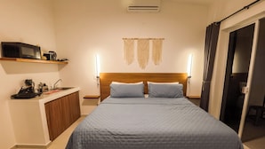 A bedroom with a bed, bedside tables, a microwave, a small kitchenette, and a sliding door. - Tayga studios Cancun (Cancun)