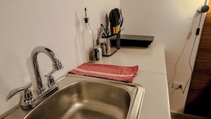A kitchen with a stainless steel sink, a wooden ceiling, and a countertop with a red cloth. - Tayga studios Cancun (Cancun)