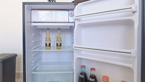 An open refrigerator with shelves containing beverages and a sign above it. - Tayga studios Cancun (Cancun)