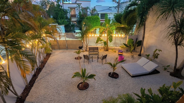 A patio area with a seating arrangement, potted plants, and a white wall. - Tayga studios Cancun (Cancun)