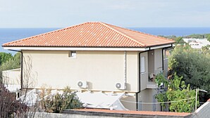 Ein eingeschossiges Gebäude mit rotem Ziegeldach, einem kleinen Fenster und einer sichtbaren Satellitenschüssel.