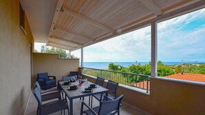 Ein Balkon mit Tisch und Stühlen, Blick auf das Meer und einer Brüstung.