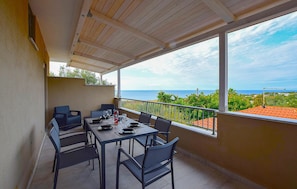 A balcony with a table and chairs, a view of the sea, and a railing. - 1 bedroom cozy apartment in Ricadi (Ricadi)
