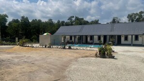 A building with a pool, outdoor seating, and a dirt area. - OYO 91303 Chalet Awie (Setiu)