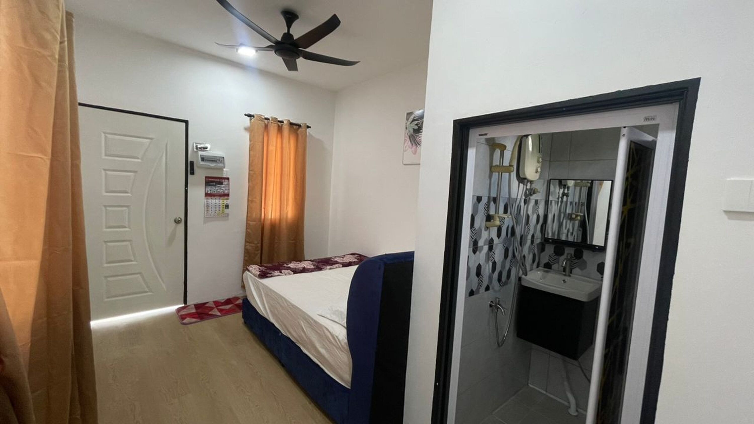 A bedroom with a bed, a ceiling fan, a door, and a bathroom visible through an open door.