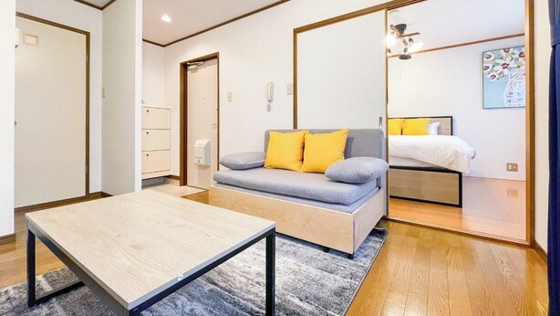 A modern room with a sofa, a small table, a bed, and a mirror. - Lavie Heights (Osaka)