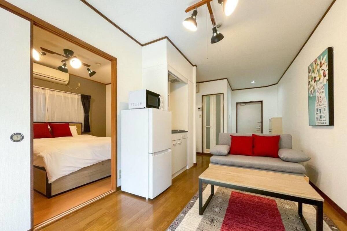 A compact room with a bed, a kitchenette, a sofa, and a dining table.