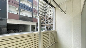 A multi-story building with a covered outdoor area, a metal gate, and a view of adjacent buildings. - Lavie Heights (Osaka)