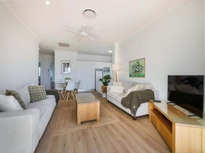 Ein modernes Wohnzimmer mit Sofa, Couchtisch, Fernseher und Deckenventilator.