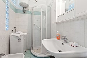 Un baño con ducha, lavabo e inodoro.
