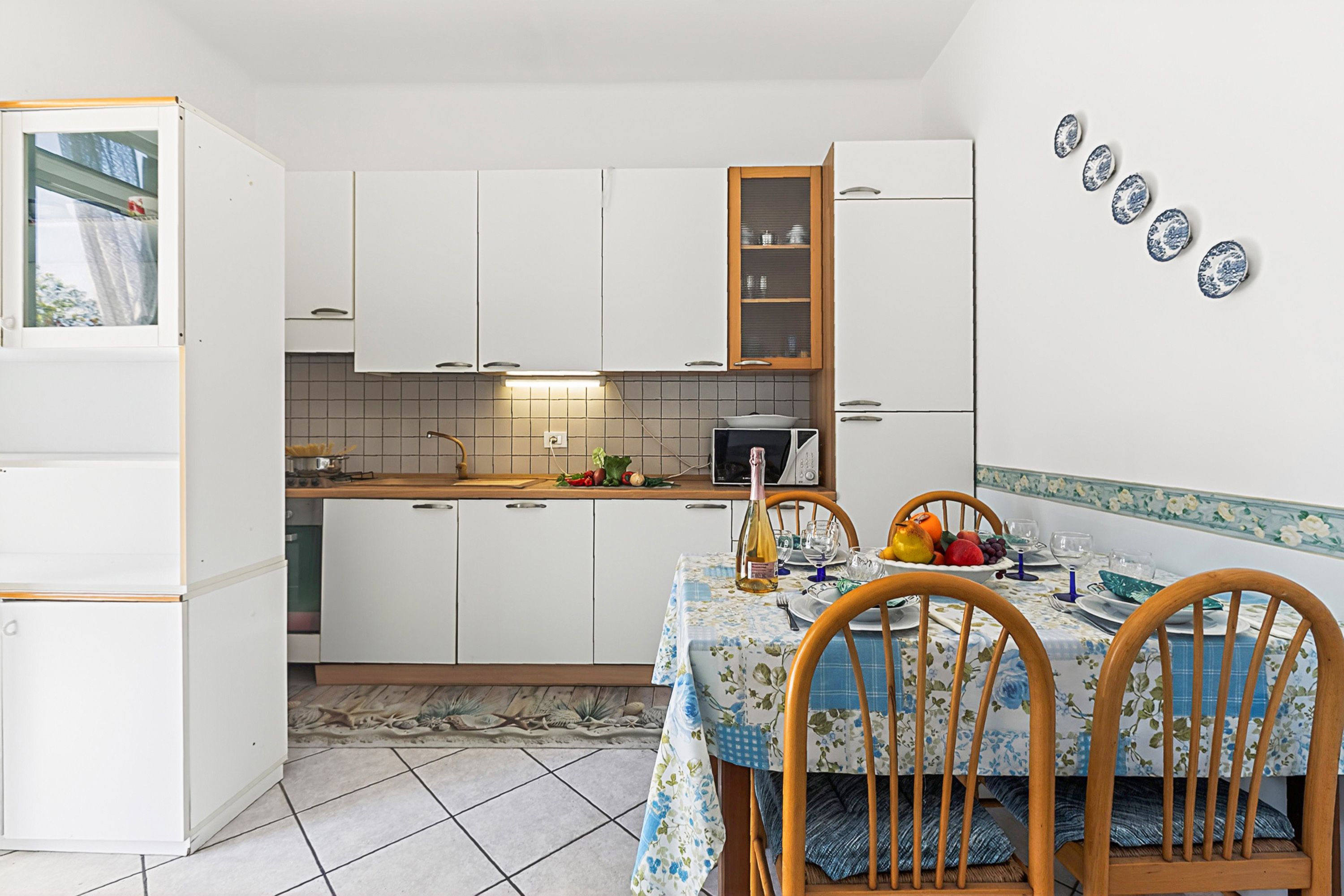 A compact kitchen with white cabinets, a microwave, and a dining area with a table set for two.