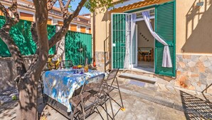 A patio with a table and chairs, a tree, and a building with green shutters and a stone wall. - Baia Serena With Terrace & Parking (San Bartolomeo al Mare)