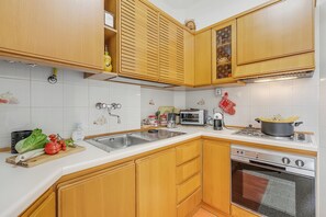 A kitchen with wooden cabinets, a sink, a stove, and an oven. - La Maison Di Amilcare Central Sanremo Balcony & Wifi (Sanremo)