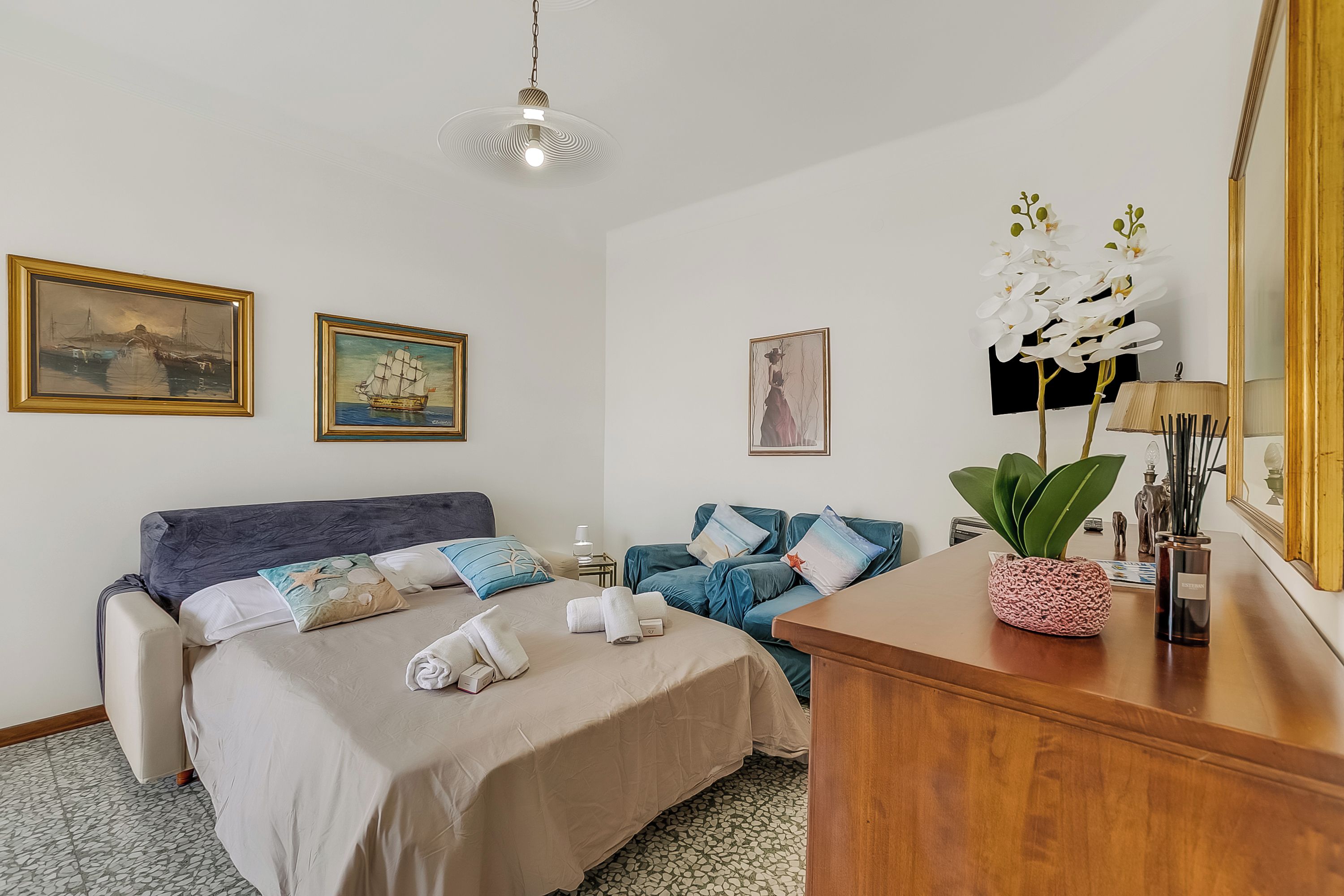Habitación de hotel con una cama, un sofá, un escritorio de madera y un espejo.