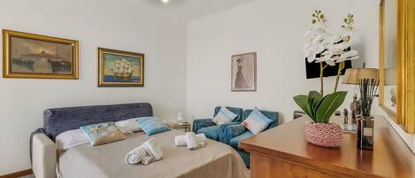 Habitación de hotel con una cama, un sofá, un escritorio de madera y un espejo.