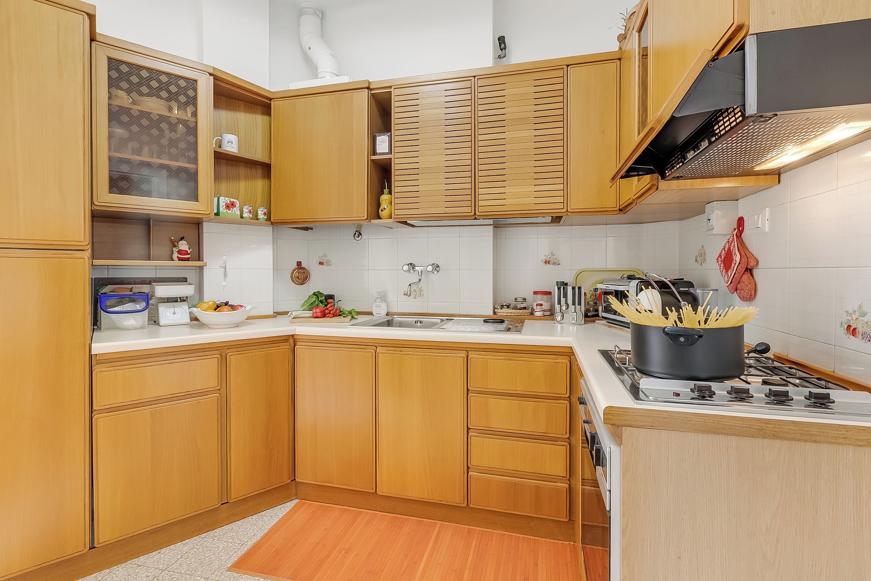 A kitchen with wooden cabinets, a white countertop, a stove, and a sink.
