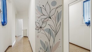 Un couloir avec un mur décoratif, un radiateur et une porte dotée d’une fenêtre.