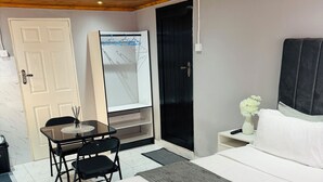 Una habitación de hotel con cama, escritorio, silla, armario y puerta.