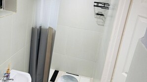 Un baño con ducha, lavamanos y piso de baldosas.