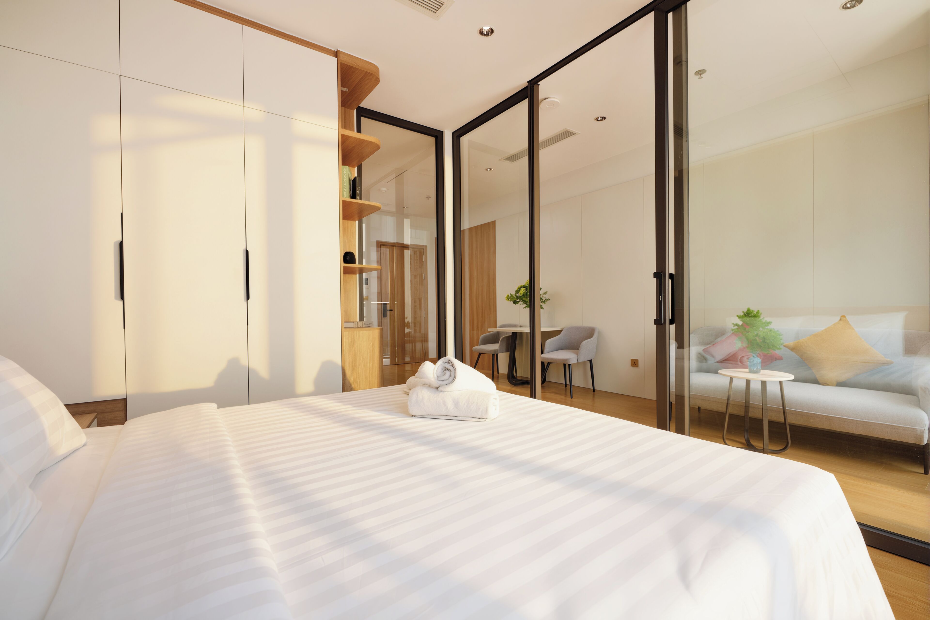 A modern hotel room with a large bed, a desk, and a sofa.