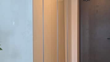 A hallway with a clock, a glass partition, and a door.