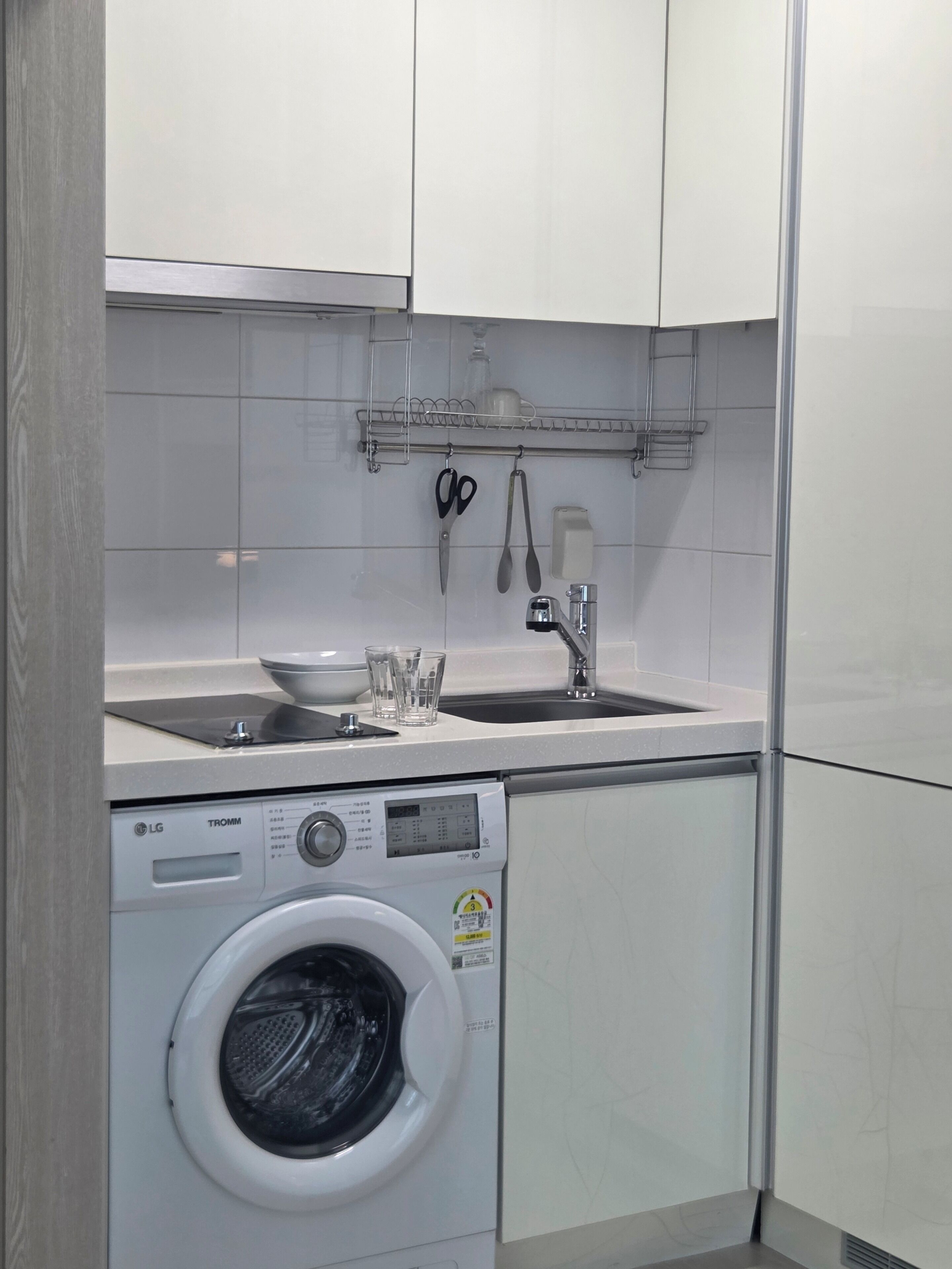 A compact kitchen with a washing machine, a sink, and a small countertop.