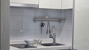 Ett kompakt kök med tvättmaskin, diskho och en liten arbetsbänk.
