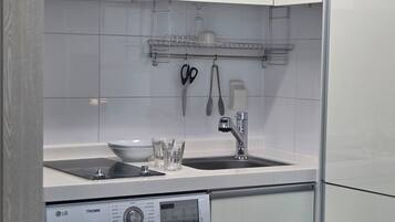 A compact kitchen with a washing machine, a sink, and a small countertop.