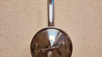A stainless steel pot with a lid on a beige carpet.