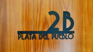 A wooden sign with '2B' and 'PLAYA DEL PUERTO' engraved. - 1818 LLC (San Juan)