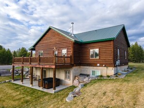Eine Blockhütte mit Balkon, Whirlpool und einem Kiesweg.