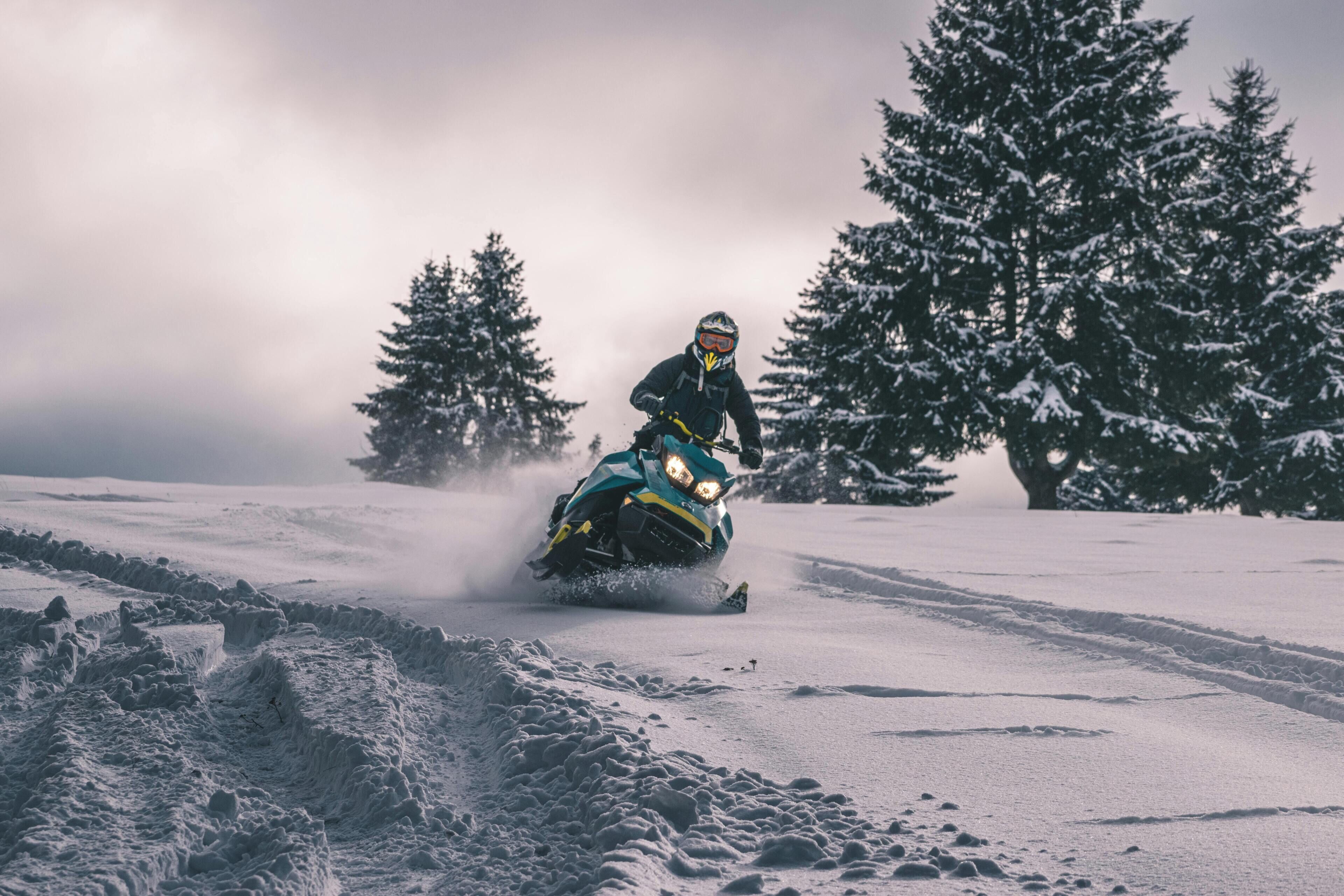 A snowmobile on a snowy path with trees in the background.