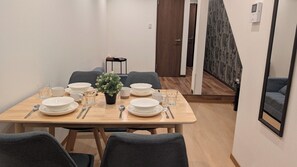 A dining area with a table set for four, chairs, a potted plant, and a door leading to another room. - The Dream Stays ShinSekai (Osaka)