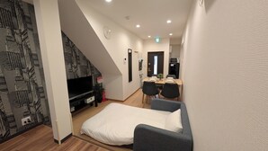 A room with a bed, a TV, a dining area, and a staircase. - The Dream Stays ShinSekai (Osaka)