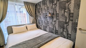 A hotel room with a bed, curtains, a patterned wall, and a window with a view. - The Dream Stays ShinSekai (Osaka)