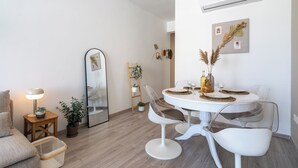 A modern dining area with a round table, white chairs, and a large mirror. - Hermes 2-BR Apt. & Balcony in Larnaca (Larnaca)