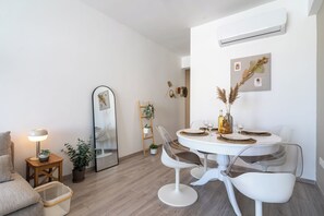 A modern dining area with a round table, white chairs, and a large mirror. - Hermes 2-BR Apt. & Balcony in Larnaca (Larnaca)